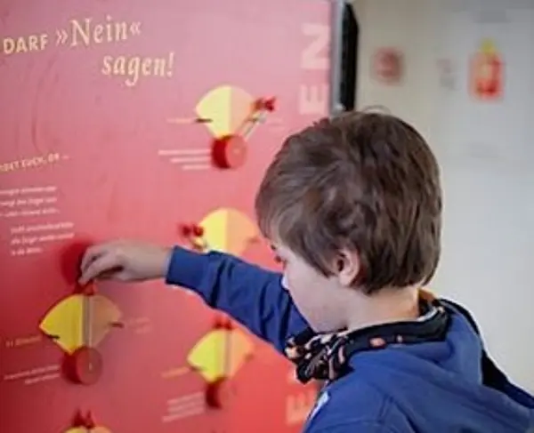 ein Junge mit blauem Pulli spielt mit der Echt klasse ausstellung